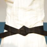 pexels photo 6253308 6253308 Detailed close-up of a martial artist adjusting a black belt on white karategi uniform.