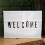pexels photo 3843285 3843285 Lightbox with 'Welcome' text on a wooden table against a green wall.